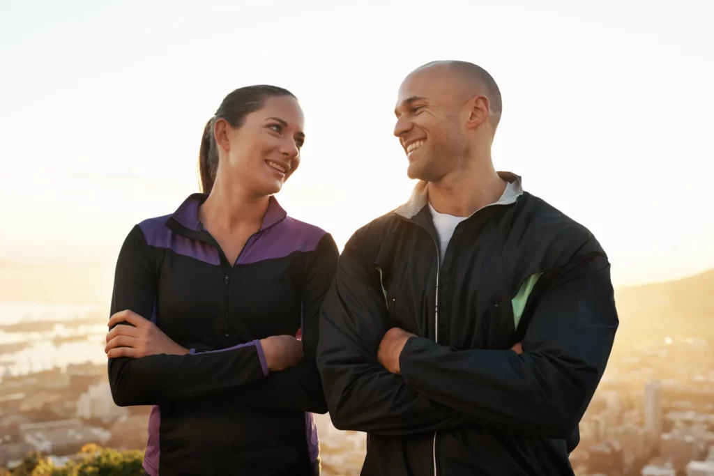 happy athletic couple smiling outdoors at sunset utc